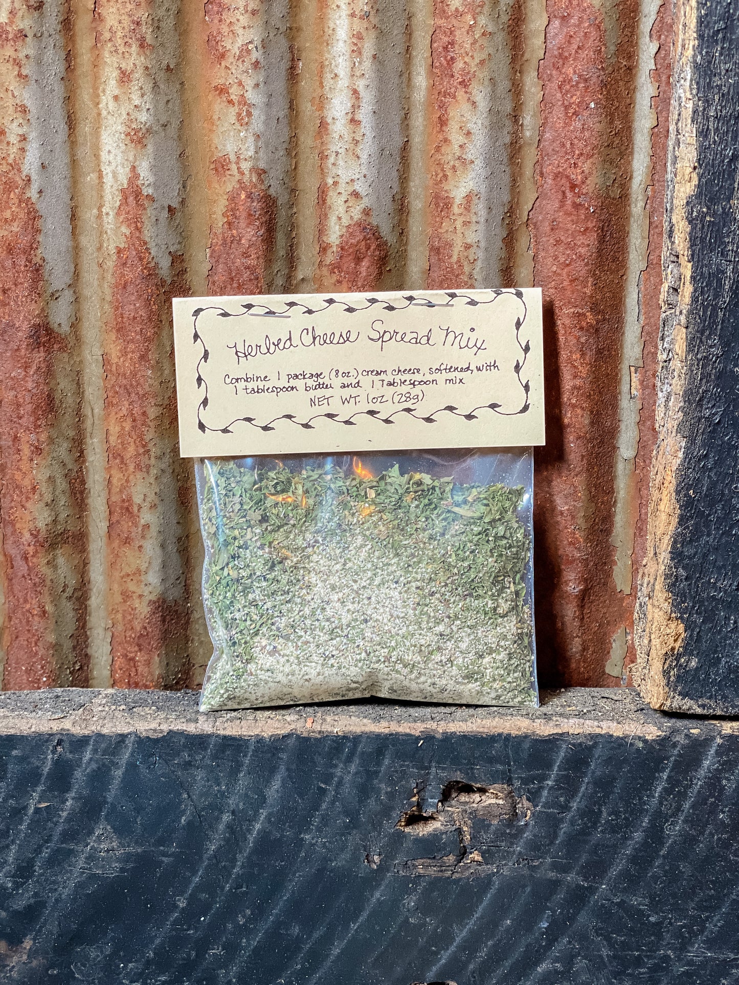 A package of Herbed Cheese Spread Mix placed against a rustic metal background.