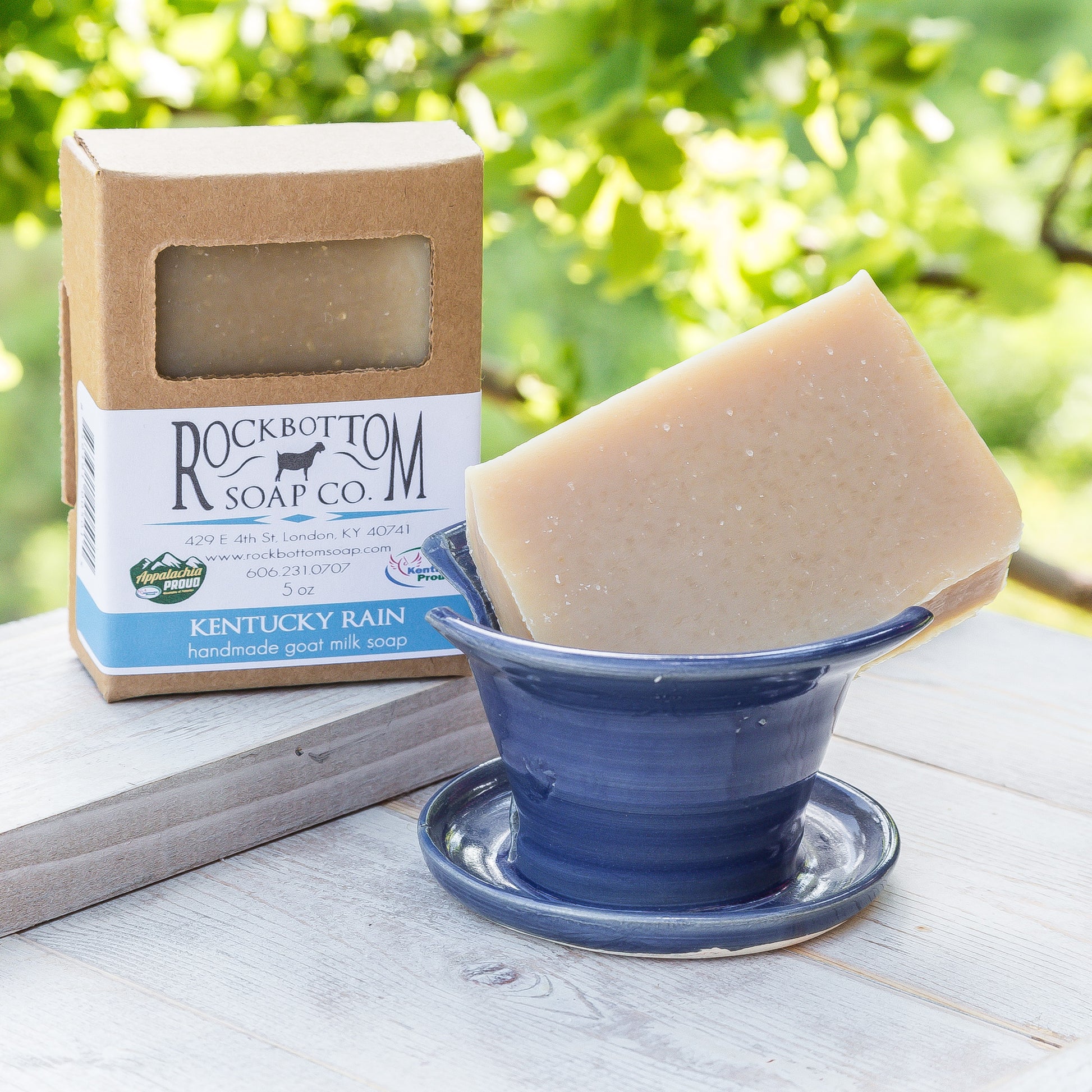 Kentucky Rain  Goat Milk Soap on a handmade pottery soap dish with green foliage background – fresh, clean artisan soap with floral and herbal notes