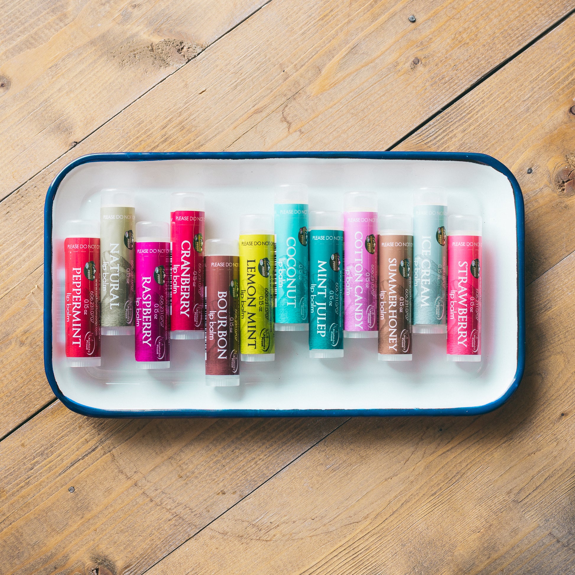 our collection of creamy natural lip balms on a metal tray on wooden background