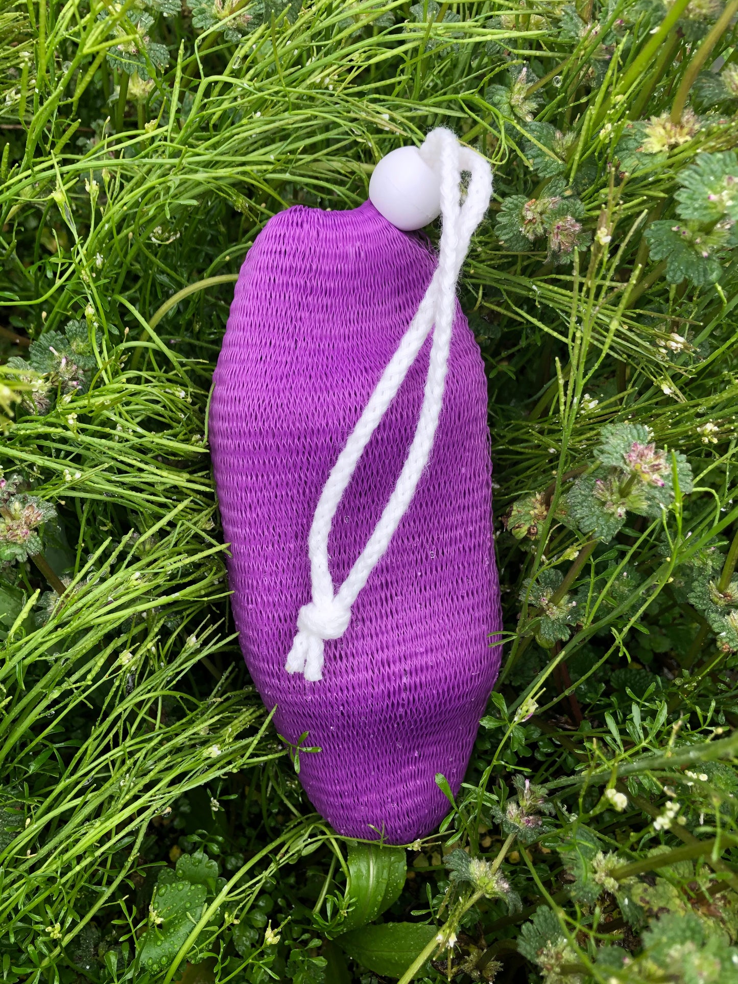 purple soap sock with bar of soap inside in an outside setting