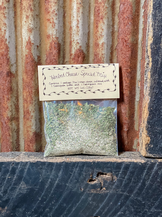 A package of Herbed Cheese Spread Mix placed against a rustic metal background.