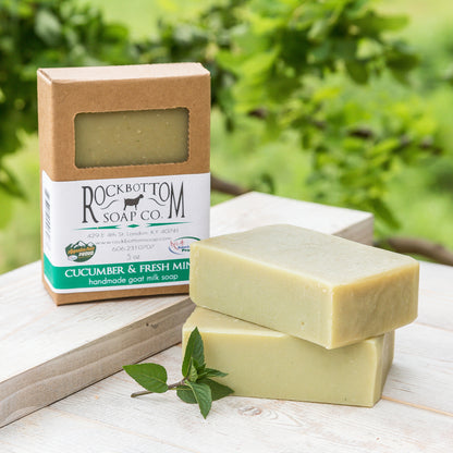 Cucumber and Mint Goat Milk Soap on a handmade pottery soap dish with green foliage background – refreshing, clean artisan soap